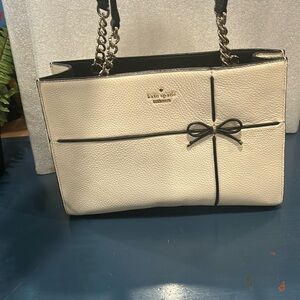 Kate spade off white rectangular purse with black bow.